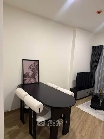Modern dining area with sleek table and chairs, adjacent to cozy living room with TV setup.