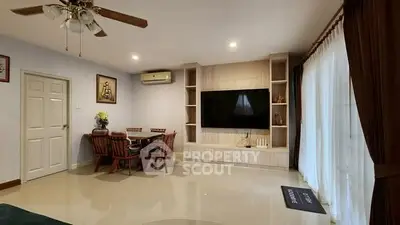 Spacious living room with modern decor and large TV, perfect for relaxation and entertainment.