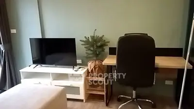 Modern living room with TV, desk, and chair in cozy apartment.