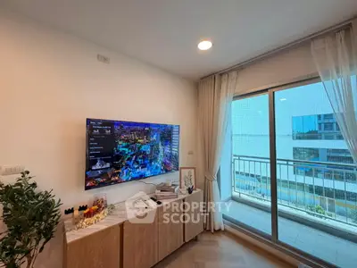 Modern living room with balcony view, featuring sleek TV setup and elegant decor.