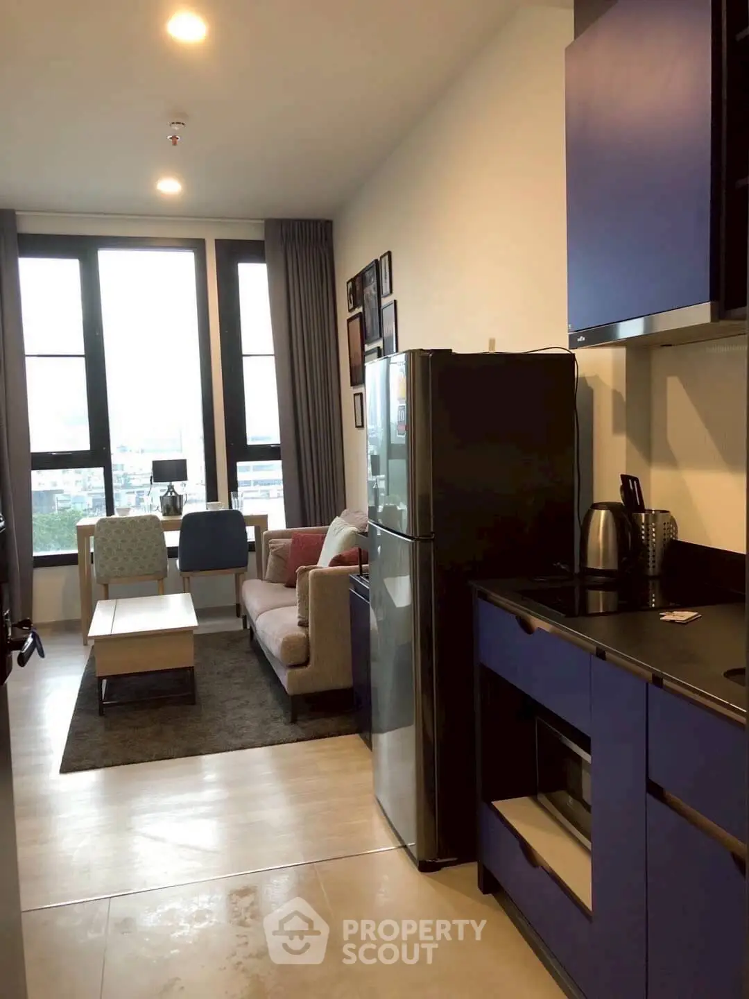 Modern open-plan living room and kitchen with stylish furniture and large windows.