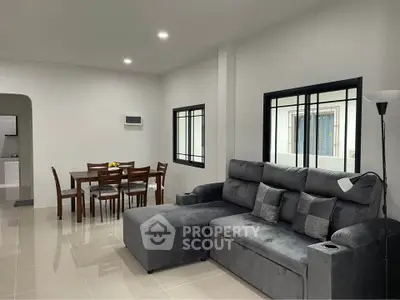 Modern living room with sleek gray sofa and dining area in open layout