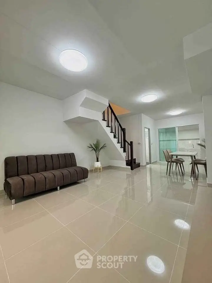 Spacious modern living room with sleek staircase and dining area, perfect for contemporary living.