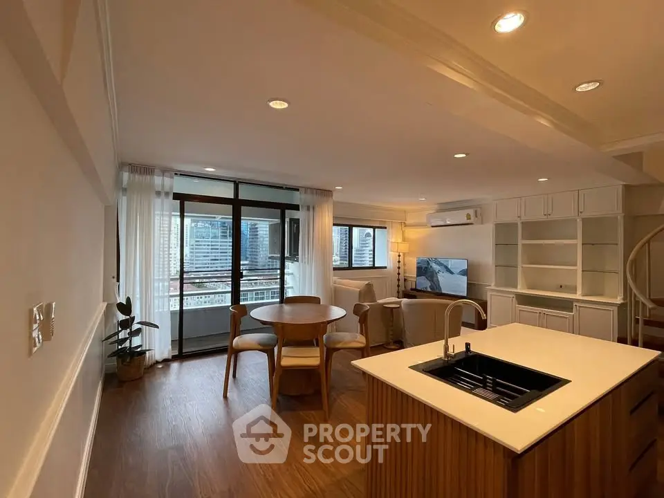 Spacious open-plan living room with modern kitchen and city view balcony.