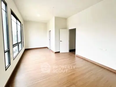 Spacious empty room with large windows and wooden flooring, perfect for customization.