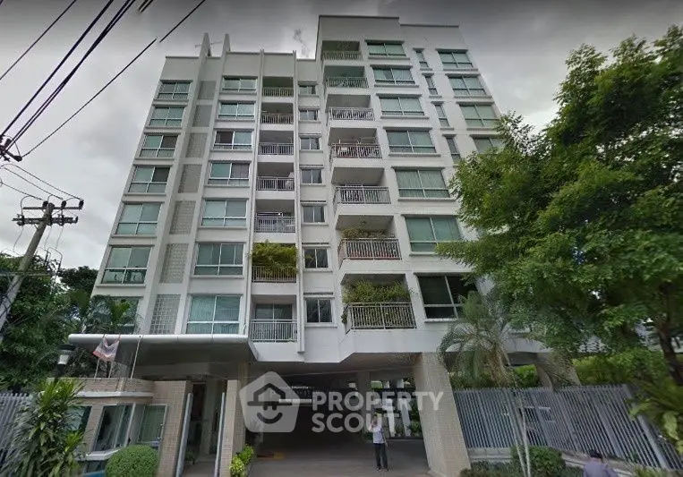 Modern multi-story residential building with lush greenery and secure entrance.