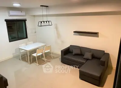 Modern living room with sleek furniture and dining area, featuring a stylish sofa and contemporary lighting.