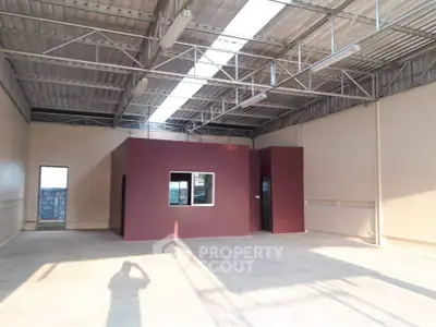 Spacious industrial warehouse interior with high ceilings and ample natural light.