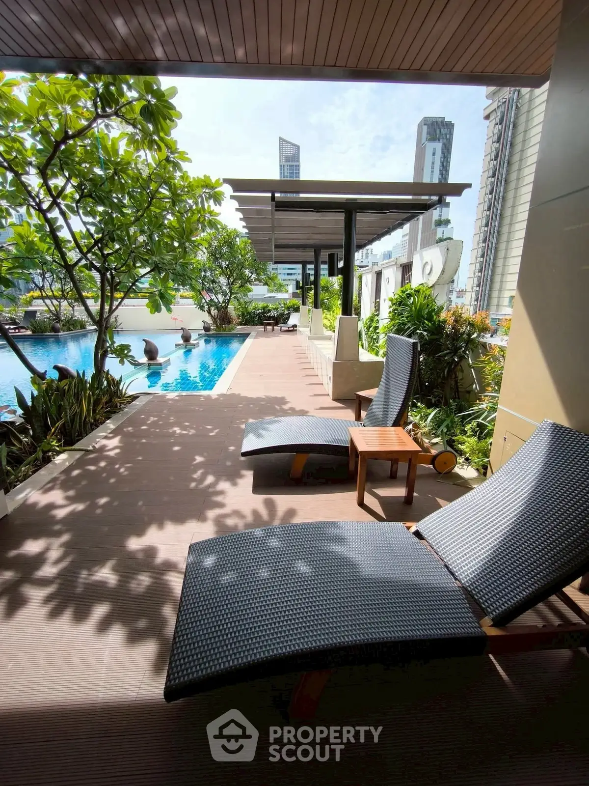 Luxurious poolside area with modern lounge chairs and lush greenery, perfect for relaxation in a high-rise setting.