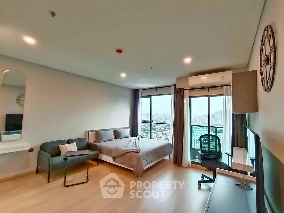 Modern studio apartment with city view, featuring cozy bed, stylish decor, and ample natural light.