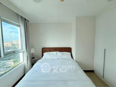 Bright bedroom with city view, featuring a cozy bed and ample natural light, perfect for relaxation.
