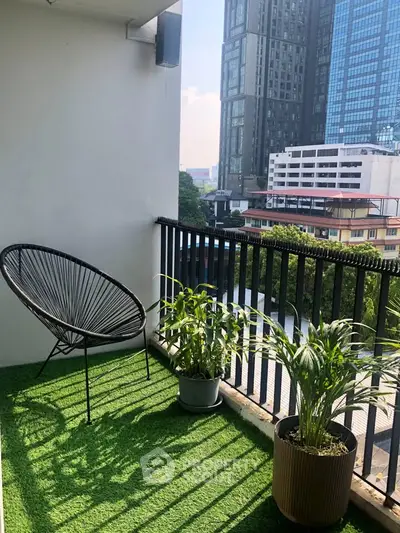 Charming balcony with city view, featuring modern chair and lush plants, perfect for relaxation.