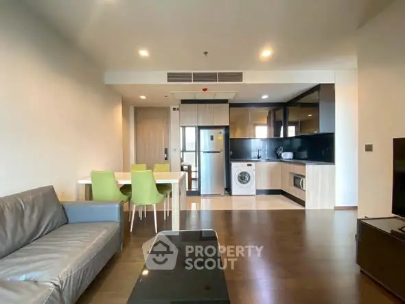Modern open-plan living room with kitchen featuring sleek appliances and stylish decor.
