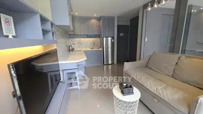 Modern open-layout living room with sleek kitchen and cozy seating area, perfect for urban living.