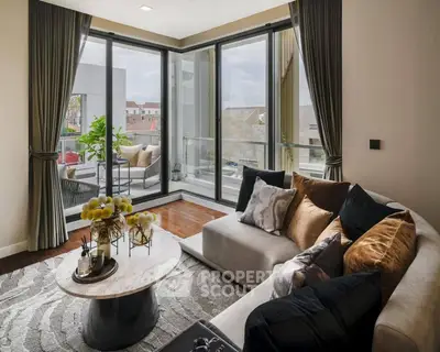 Luxurious living room with elegant decor and large windows opening to a balcony with a view.