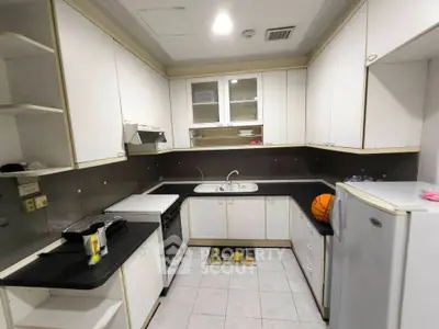 Modern kitchen with sleek white cabinets and black countertops, featuring a compact layout and essential appliances.