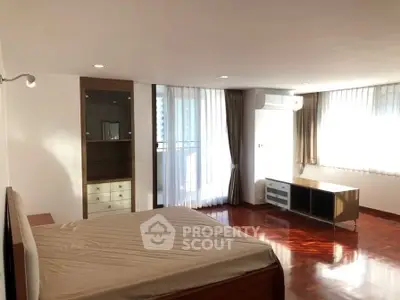 Spacious bedroom with hardwood floors and large windows in modern apartment