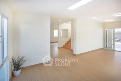 Spacious open-plan living area with wooden flooring and natural light