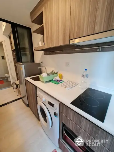 Modern kitchen with washing machine and electric stove in compact apartment