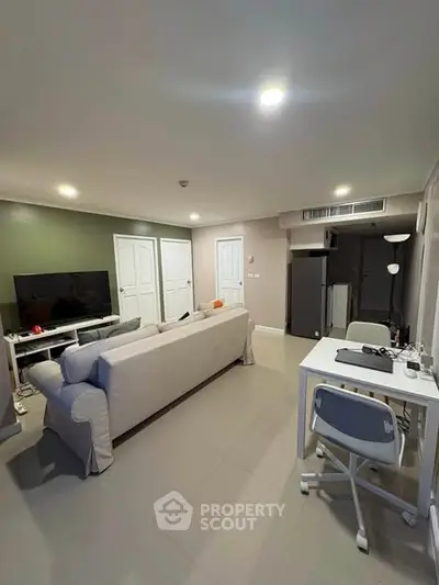 Modern living room with cozy sofa, TV, and compact workspace in stylish apartment.