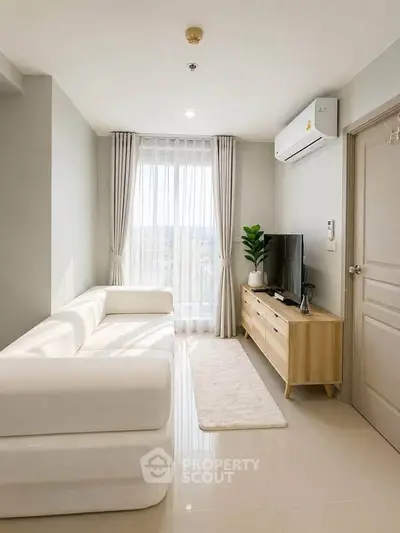 Modern living room with sleek white sofa, TV unit, and large window with curtains.