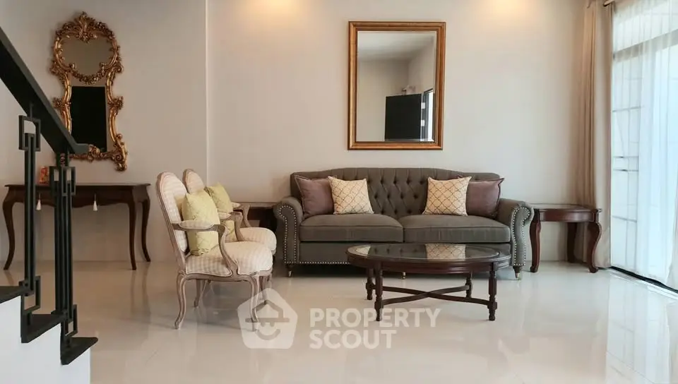 Elegant living room with plush sofa, ornate mirrors, and natural light from large windows.