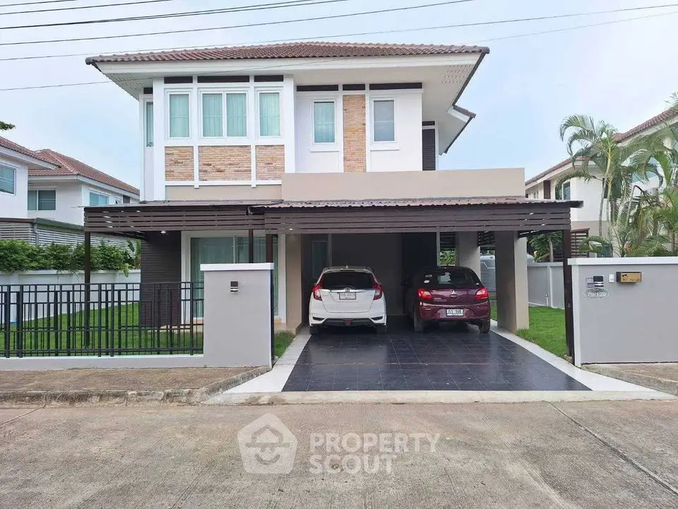 Modern two-story house with carport and landscaped garden in a suburban neighborhood.