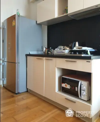 Modern kitchen with sleek cabinets, stainless steel fridge, and microwave oven