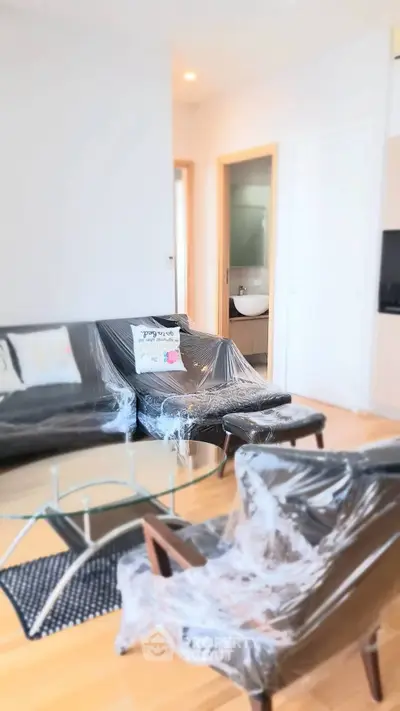 Modern living room with sleek furniture and glass coffee table in a bright apartment.