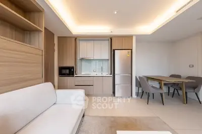 Modern open-plan living room with sleek kitchen and dining area, featuring neutral tones and contemporary furniture.