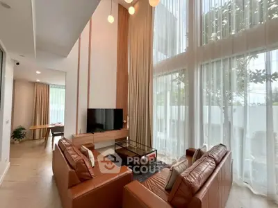 Luxurious high-ceiling living room with modern decor and large windows for natural light.