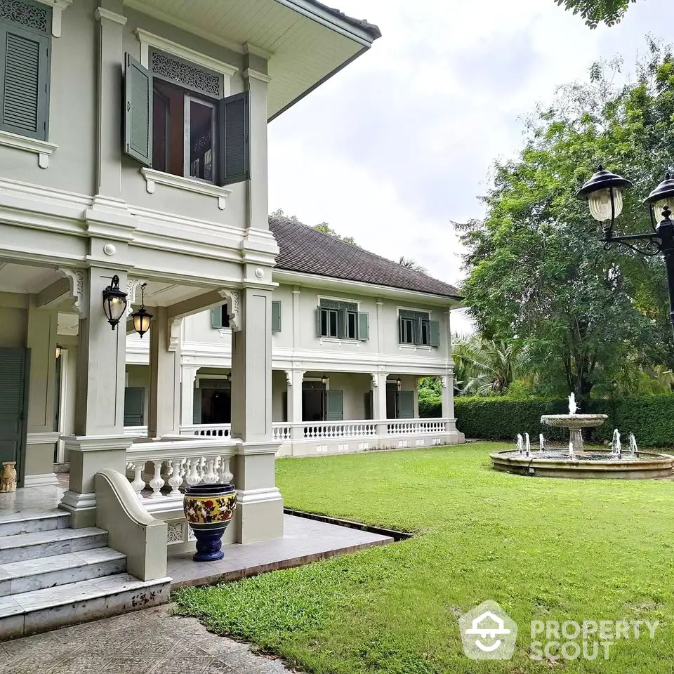 Elegant colonial-style home with lush garden and charming fountain