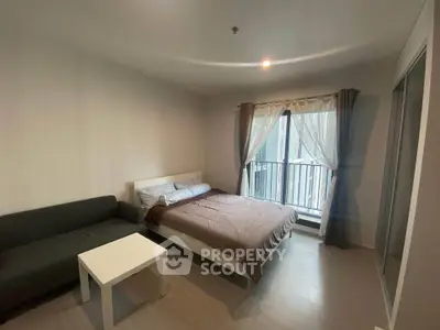 Modern bedroom with cozy bed, stylish sofa, and natural light from large window.