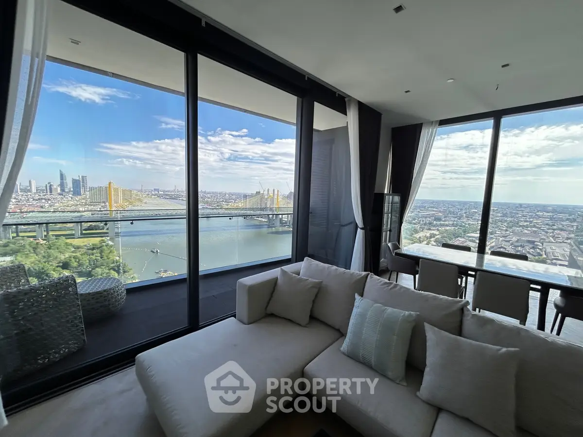 Luxurious living room with panoramic city and river views from high-rise apartment.