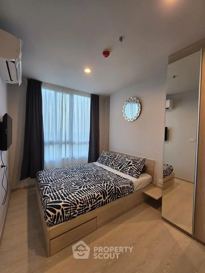 Modern bedroom with stylish decor and large window in a cozy apartment.
