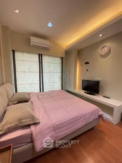 Cozy bedroom with modern decor, featuring a comfortable bed, TV, and ambient lighting for a relaxing atmosphere.