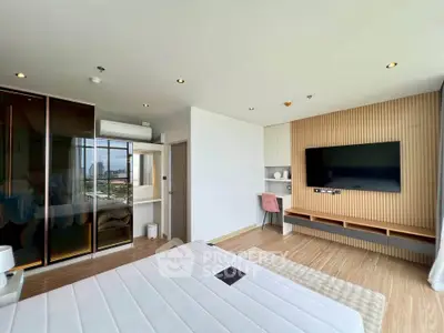 Modern bedroom with sleek design, large TV, and city view from window.