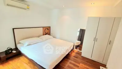 Spacious bedroom with wooden flooring and modern wardrobe