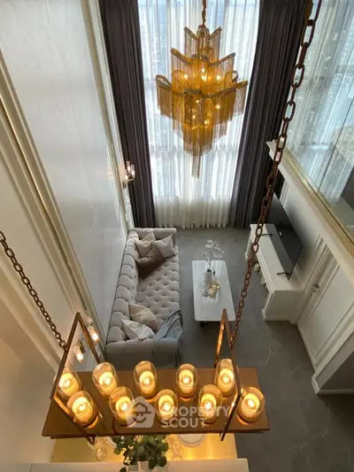 Luxurious high-ceiling living room with elegant chandelier and plush sofa