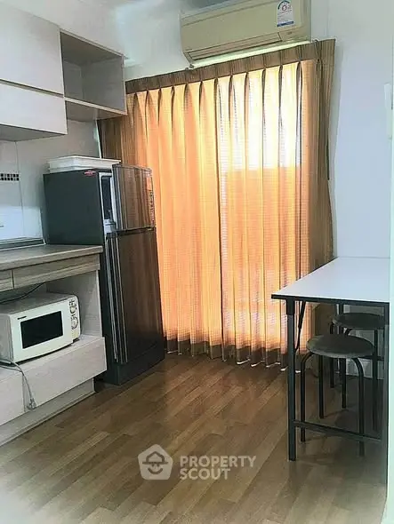 Cozy kitchen with wooden flooring, modern appliances, and natural light through elegant curtains.