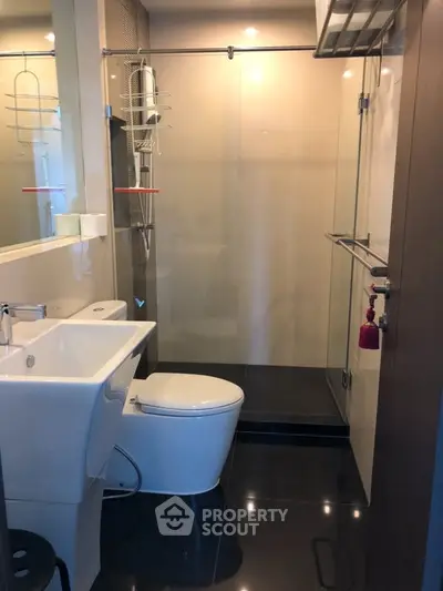 Modern bathroom with sleek fixtures and glass shower enclosure in a contemporary apartment.