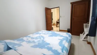 Cozy bedroom with cloud-patterned bedding and wooden wardrobe, ideal for restful nights.