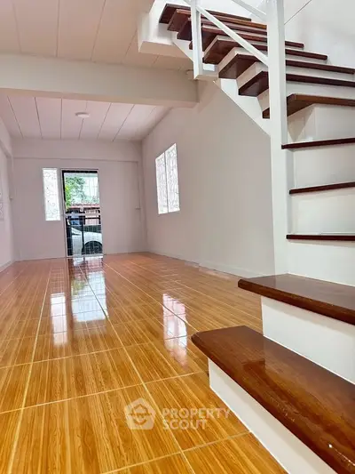 Spacious open-plan living area with wooden flooring and modern staircase