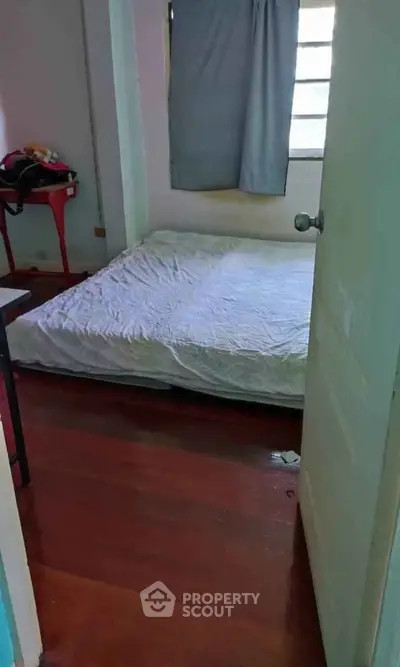Cozy bedroom with wooden flooring and natural light, perfect for a peaceful retreat.