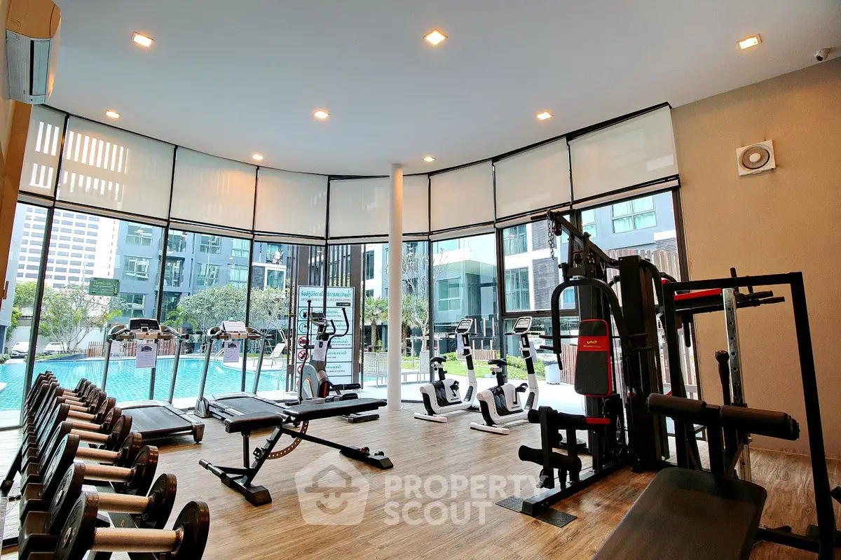 Modern gym with state-of-the-art equipment and pool view in luxury residential complex.