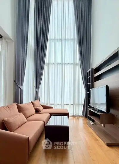 Spacious living room with high ceilings, modern furniture, and floor-to-ceiling windows.