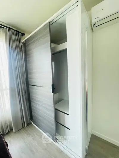 Modern bedroom with sleek sliding wardrobe and air conditioning unit, perfect for stylish living.