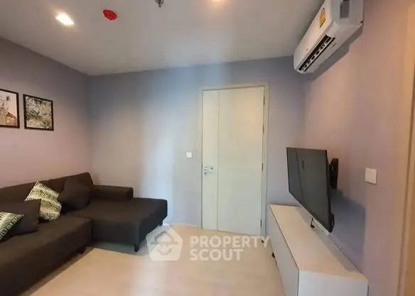 Modern living room with sleek furniture and wall-mounted TV in a cozy apartment.