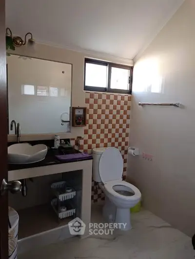 Modern bathroom with stylish sink and checkered tile accent wall.