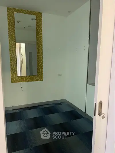 Compact interior space with patterned mirror and blue carpet tiles.